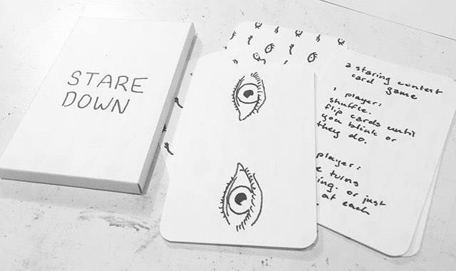 The box, a card with a drawing of open eyes, a card listing the rules to the game, and part of the back of another card.