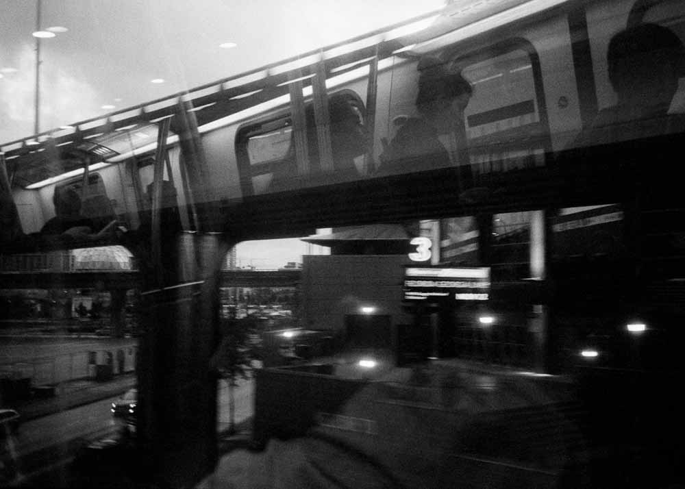 Day. An overpass, and road below. Reflected: passengers and windowframes, but no reflections against bright areas of sky.