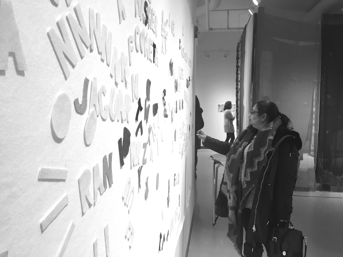 The felt board installed in an art gallery. A woman reaches out to make an adjustment.